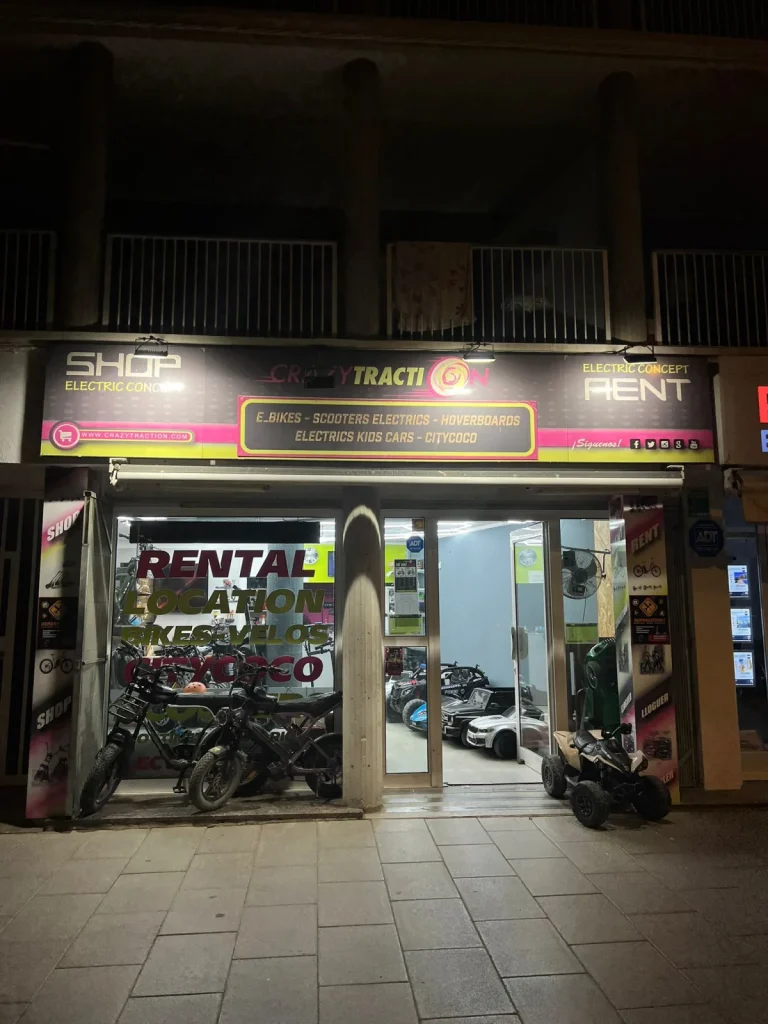 La tienda LuxyRent de noche con los coches eléctricos para niños al fondo